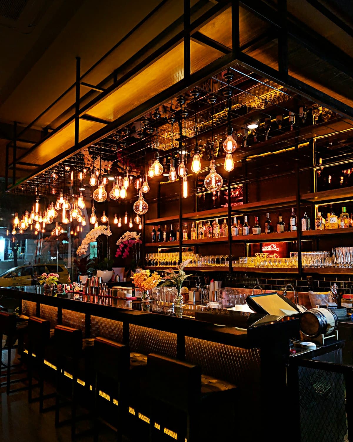 The bar at Marrow at night, lit warm under pendant lights with the back-bar bottles behind
